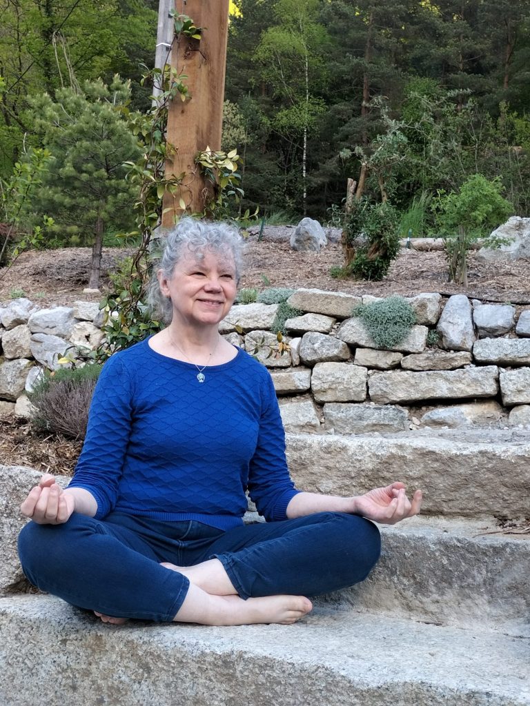 Patricia Giustiniani, professeure de yoga, assise en tailleur en extérieur