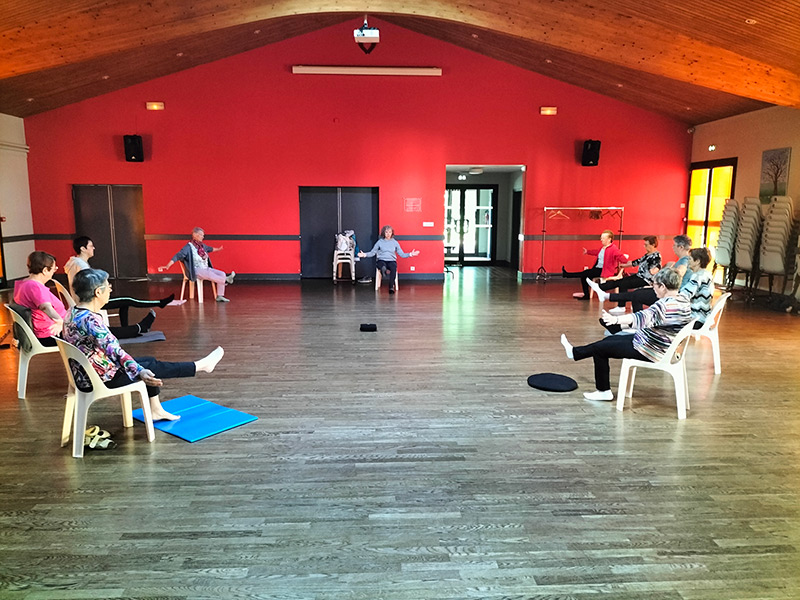 Cours de yoga sur chaise dans une salle communale
