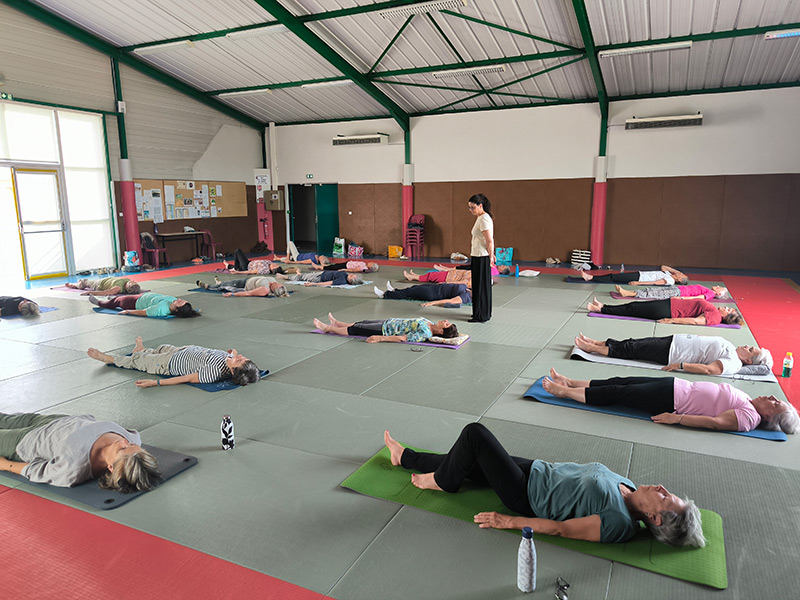 Cours collectif de yoga en salle, pratiquants en relaxation