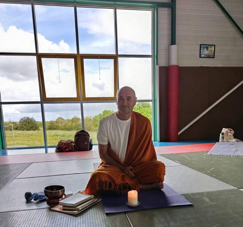 Dom Ananda assis en méditation dans la salle des Arts Martiaux de La Verrie