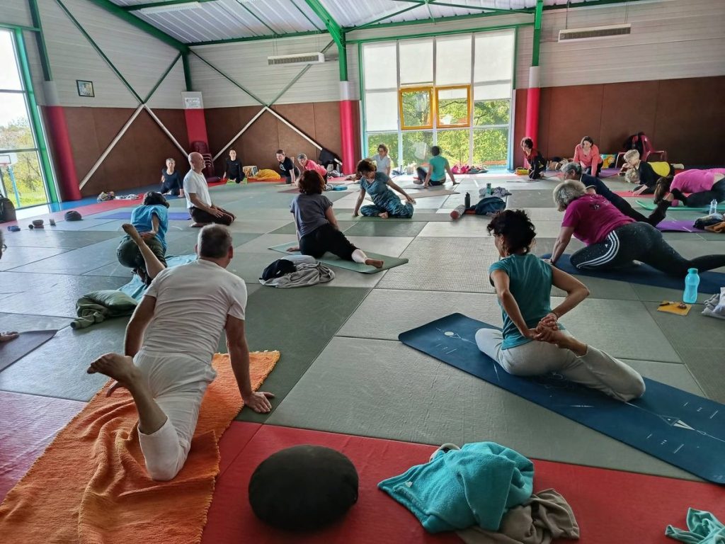 Participants pratiquant le yoga lors de la journée avec Dom Ananda, salle des Arts Martiaux de La Verrie