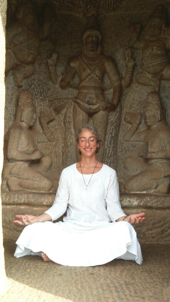 Anouk vêtue de blanc, en méditation devant des sculptures de temple en Inde
