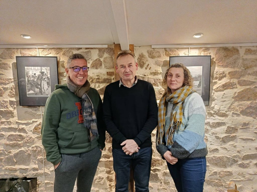 Trois membres du bureau de l’association Graine de Lotus, debout devant un mur en pierre
